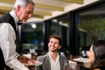 senior waiter serving couple at restaurant