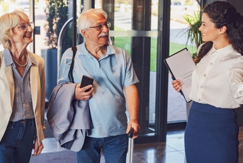 cheerful hotel receptionist greeting senior couple