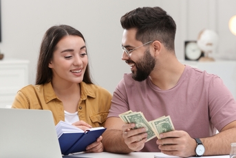 young couple counting money at home