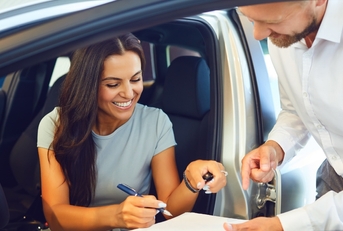 happy woman buying car at showroom