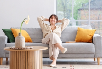 happy woman relaxing on grey sofa
