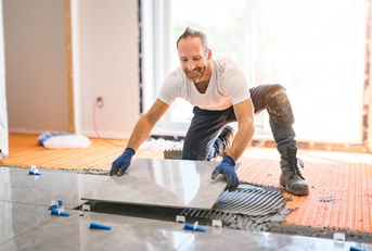 Handyman installing tile on floor