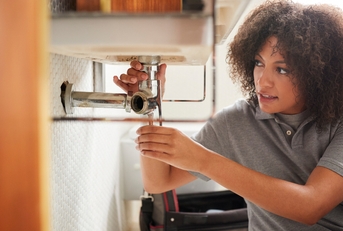Female plumber fixing bathroom sink