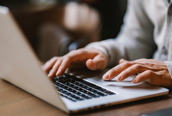  hands typing on a laptop
