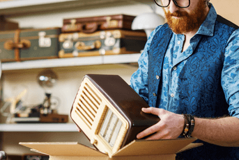 A man places a vintage radio into a cardboard box.
