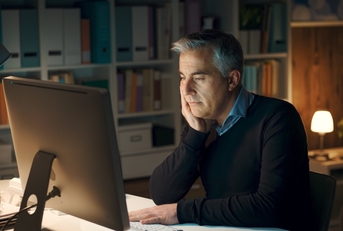 senior man working from home late night