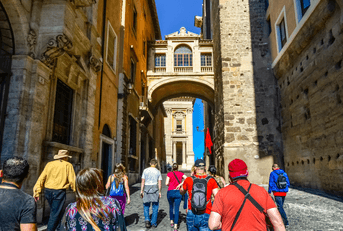 A group of unidentifiable tourists follow a tour guide in Rome