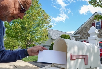 taking white envelope from letterbox