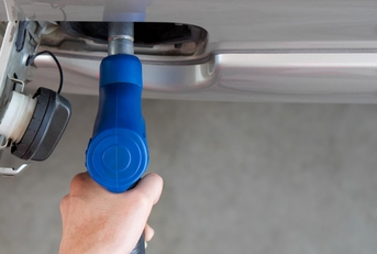 Hand holding blue gas pump nozzle