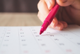 Hand with pen writing on calendar page closeup