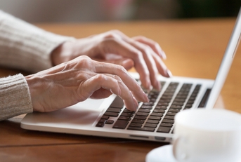 Mature female person typing text on keyboard