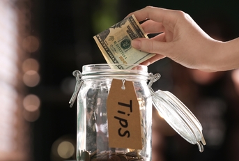 woman putting tips into glass jar