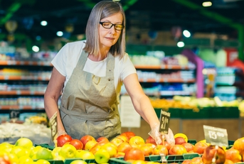 store worker lays out and sorts fruit