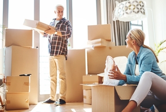couple packing boxes together in their home