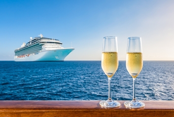 two glasses of champagne on wooden railing at sunset