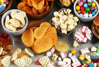 Salty snacks. Pretzels, chips, crackers and candy sweets on table 