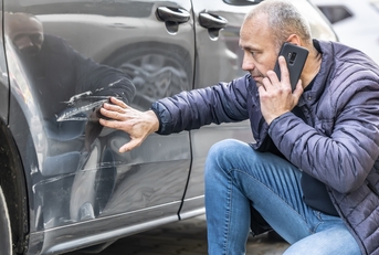 Man looking at car damage