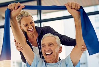 physical therapist helping a senior patient stretch with a stretch band