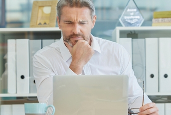 businessman thinking infront of laptop