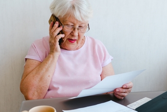senior woman holding papers while talking on mobile phone