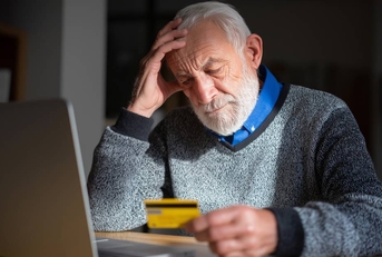 Senior man looking worried while holding a credit card