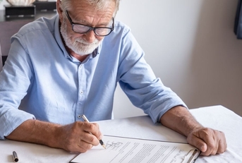 Senior old man elderly examining and signing last will and testament