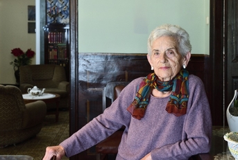 75-year-old woman standing in a dining room