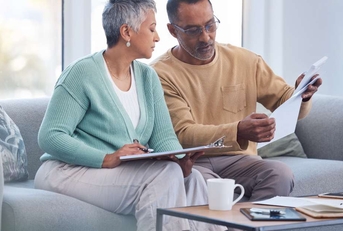couple on sofa with bills paperwork and insurance 