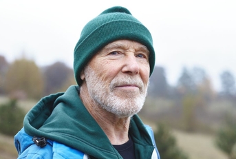 older man outdoors wearing a green beanie
