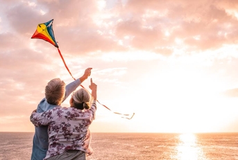 Senior couple flying kite by the water