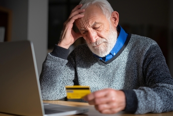 senior man looking worried while holding credit card