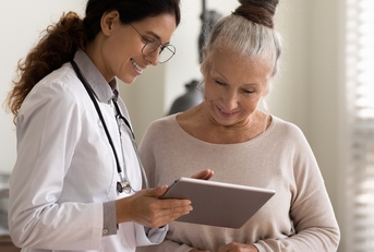 doctor and senior patient look at tablet screen