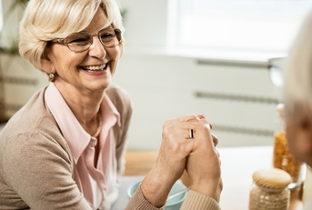 Senior woman holding her spouse's hand and smiling