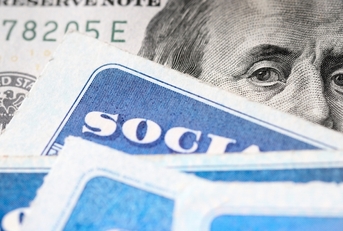Dollar bill with Benjamin Franklin&#x27;s eyes looking and Social Security cards