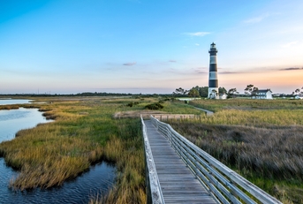 North Carolina outer banks showing lighthouse in background and bridge next to water in foreground