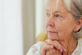 older woman thinking with hands under chin
