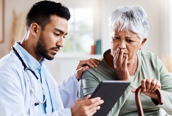 older woman sitting with doctor looking concerned