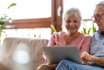 senior couple on couch with laptop