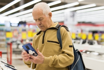 Senor man buying phone in showroom of digital electronic goods store 
