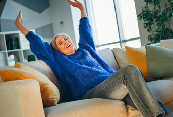 Woman happy and relaxed with arms up on the couch