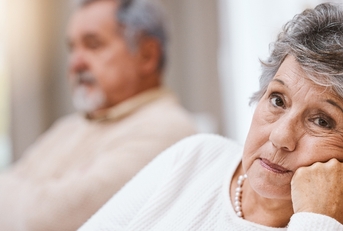 Bored senior woman looking while husband is in the back