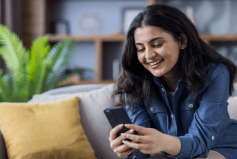 Woman sitting on couch scrolling on cell phone