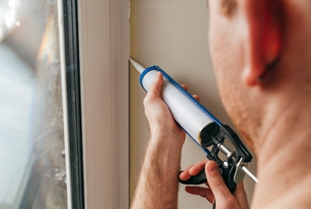 A man caulking a window