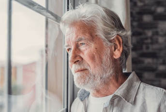 contemplative older man looking out window