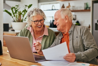 Older couple smiling while working on financial paperwork
