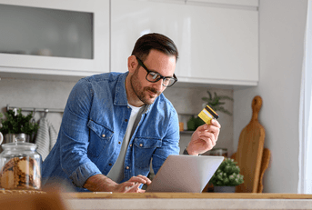 Man with credit card searching on laptop