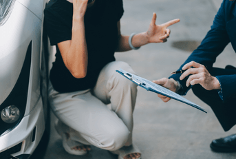 Car insurance agent and client assessing damage