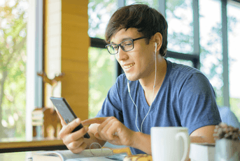 Man at coffee shop with cell phone and earbuds