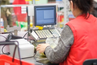 Cash desk with cashier serves customer in modern supermarket 