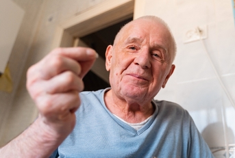 Old man in his 80's showing something on his hands and smiling